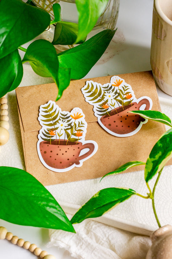Floral Tea Cup Stickers laying on a Kraft paper envelope surrounded by plants