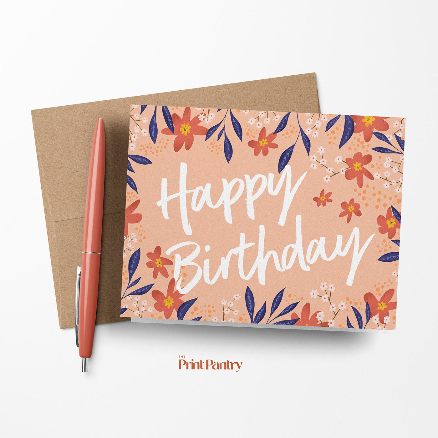 Floral Birthday Greeting Card laying on a Kraft paper envelope with a pen