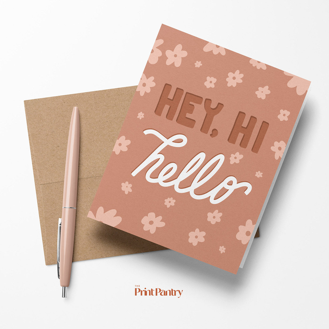 Hey, Hi, Hello Greeting Card laying with a Kraft paper envelope and pen