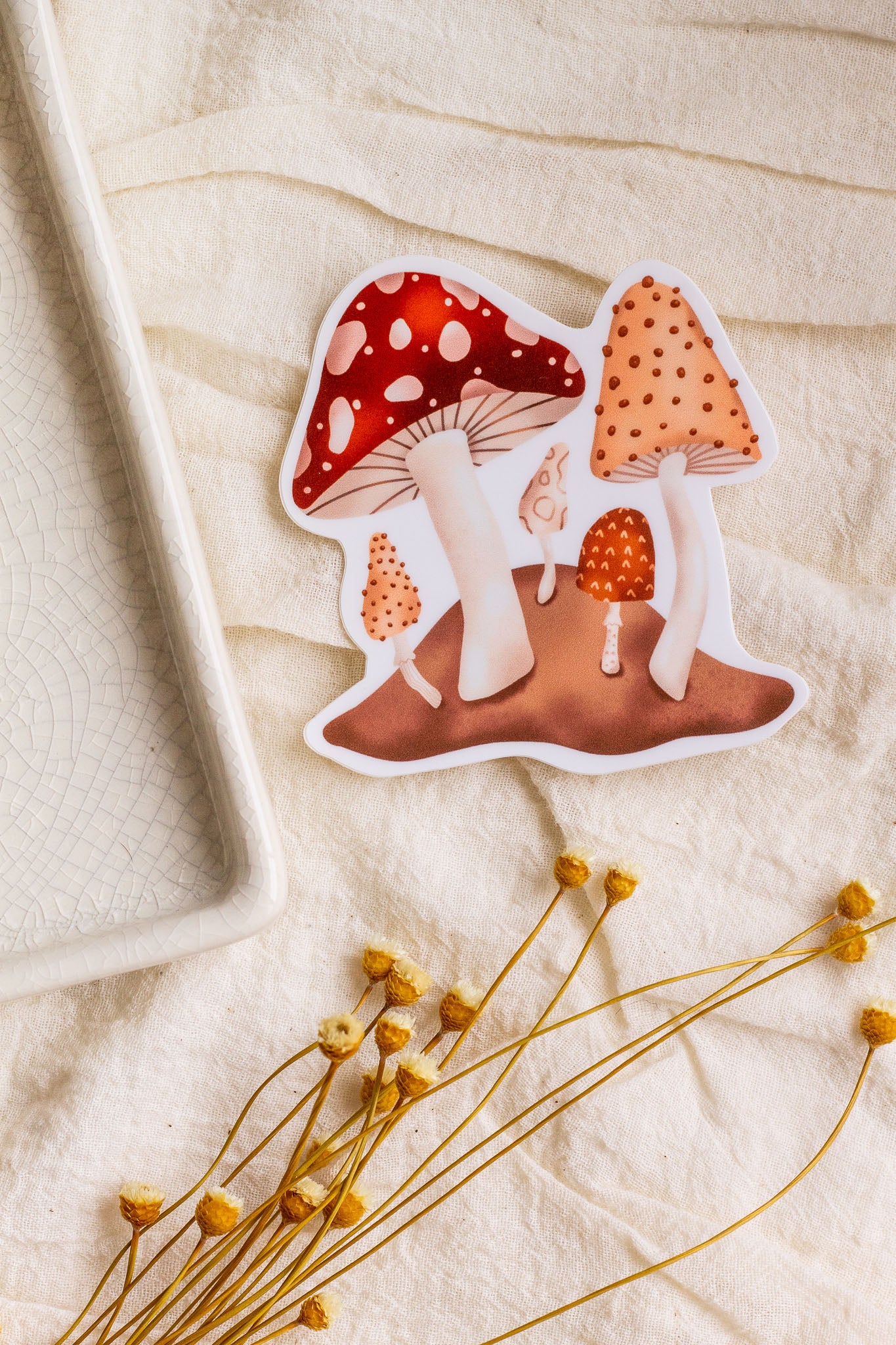 Forest Mushroom Vinyl Sticker laying on decorative fabric with flowers next to it