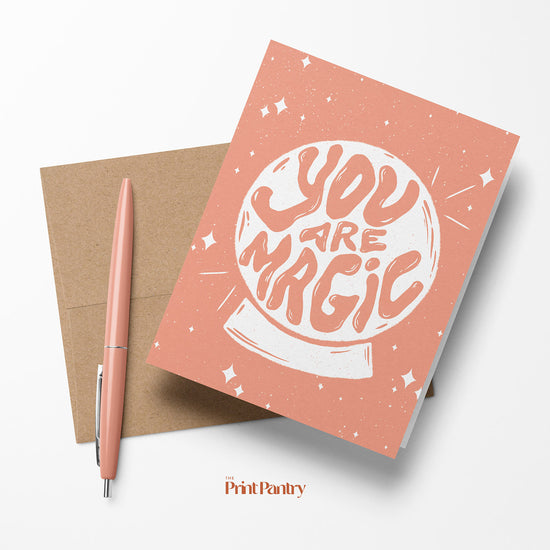 You Are Magic Greeting Card laying on a Kraft paper envelope with a pen