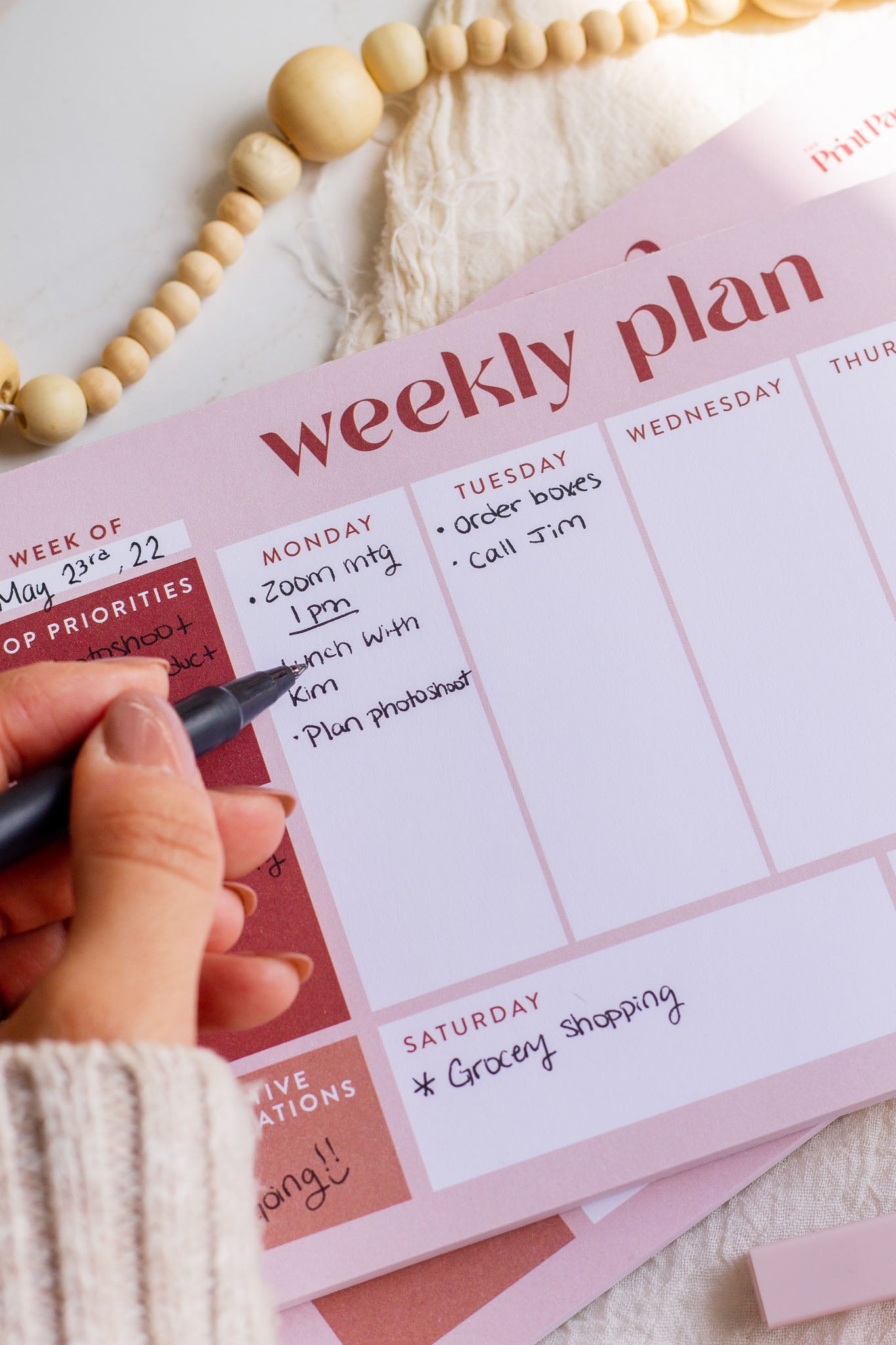 Woman writing on a Weekly Plan Notepad