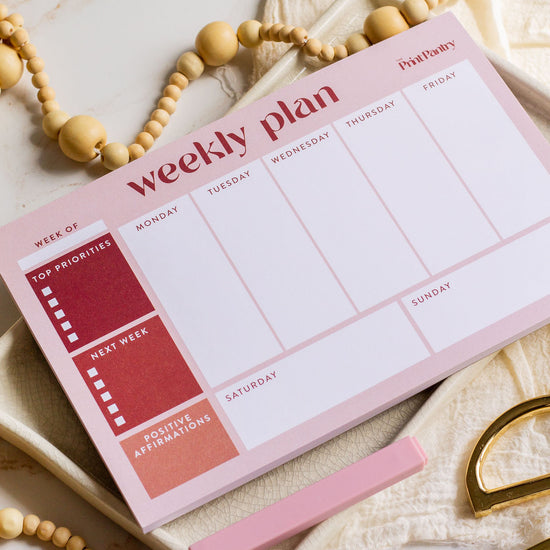Weekly Plan Notepad laying on a decorative tray with markers and scissors laying next to it
